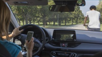 A driver is distracted by her phone while following a cyclist
