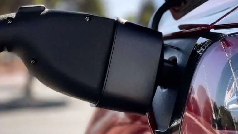 A Tesla charging with an adapter for use at non-Tesla charging stations