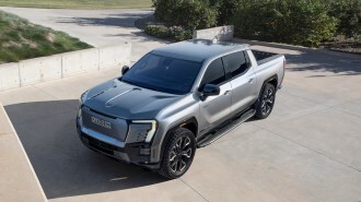 Silver 2024 GMC Sierra EV Denali Edition parked in driveway.