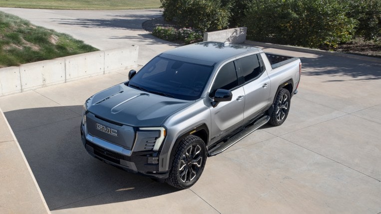 Silver 2024 GMC Sierra EV Denali Edition parked in driveway.