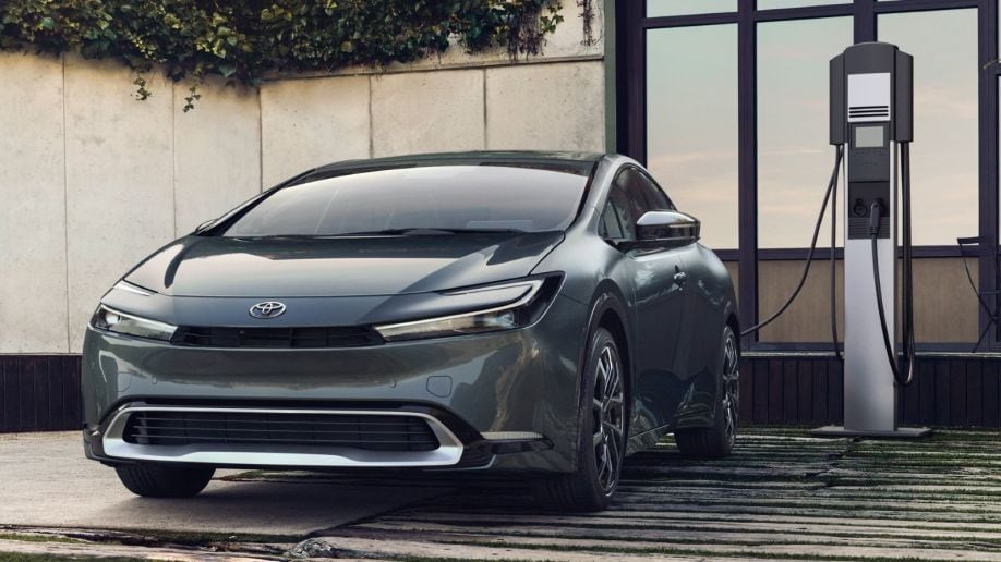 The redesigned 2023 Toyota Prius Prime plug-in hybrid shown from the front, plugged in and charging.