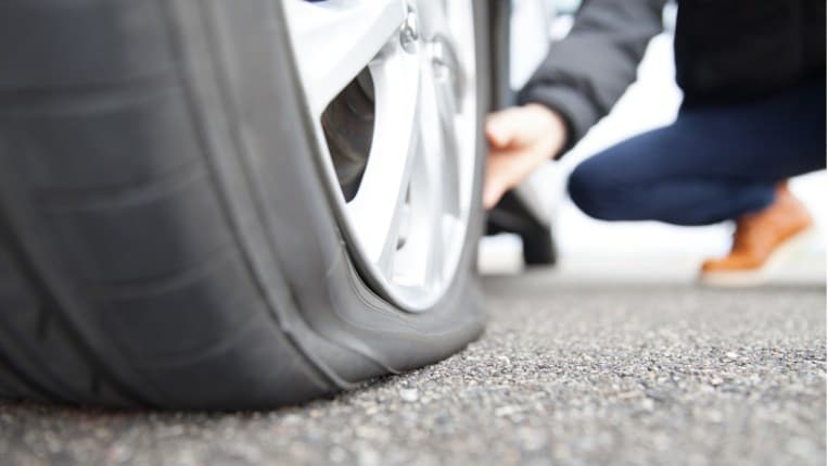 Driver inspecting a car's flat tire