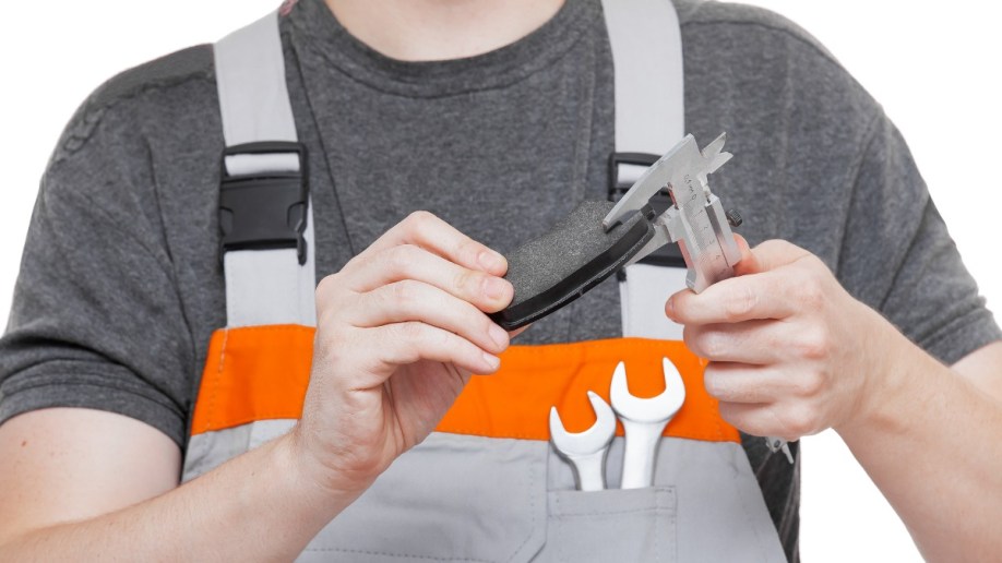 Mechanic using calipers to check brake pads.