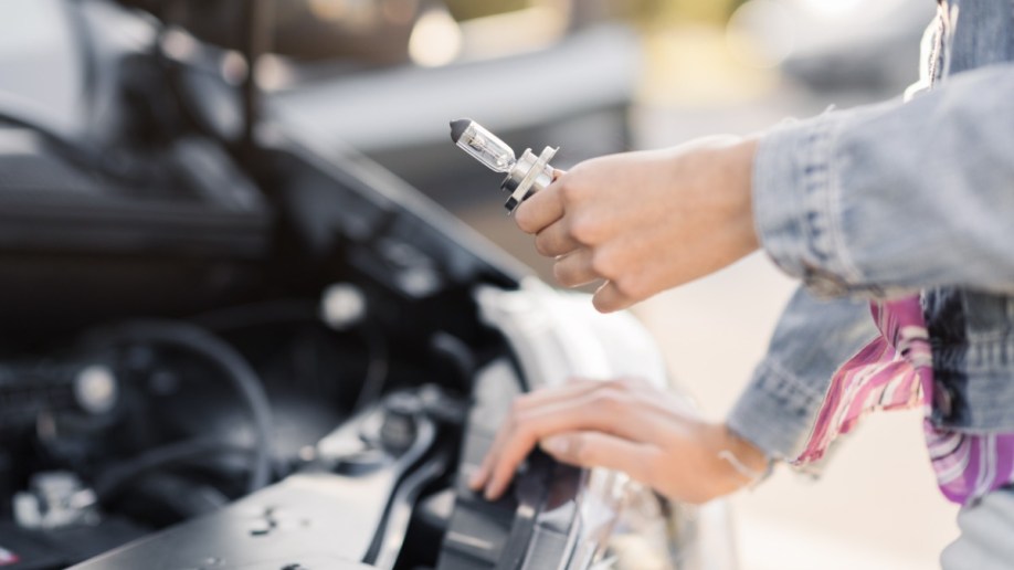 A person replacing a car headlight bulb.