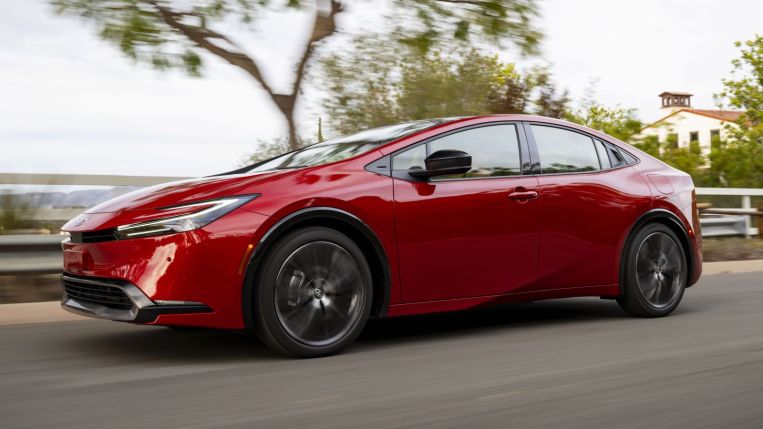 The totally redesigned 2023 Toyota Prius in red, as seen from the front while driving.