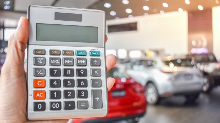 A person holding a calculator in a car dealership