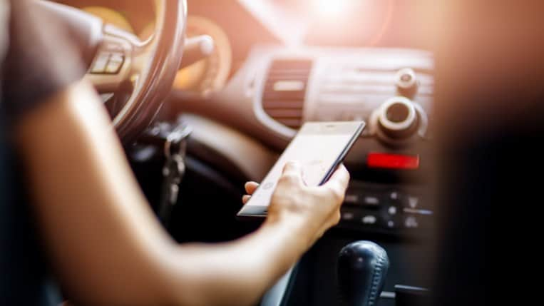 A driver checks their cell phone behind the wheel