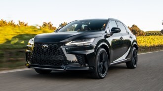 2023 Lexus RX 500h F-Sport driving near an orchard.