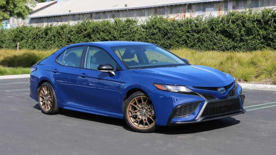 2023 Toyota Camry Hybrid Nightshade near bushes and barn.