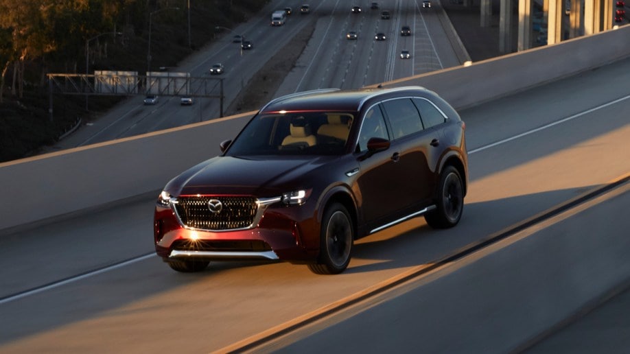 2024 Mazda CX-90 driving on freeway overpass.