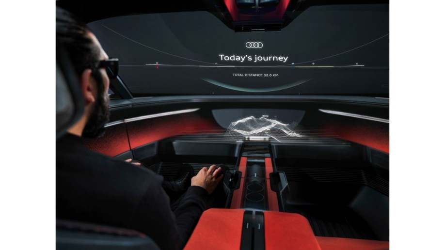 A passenger in the Audi Activesphere concept uses virtual reality goggles to see the road in a mixed-reality view