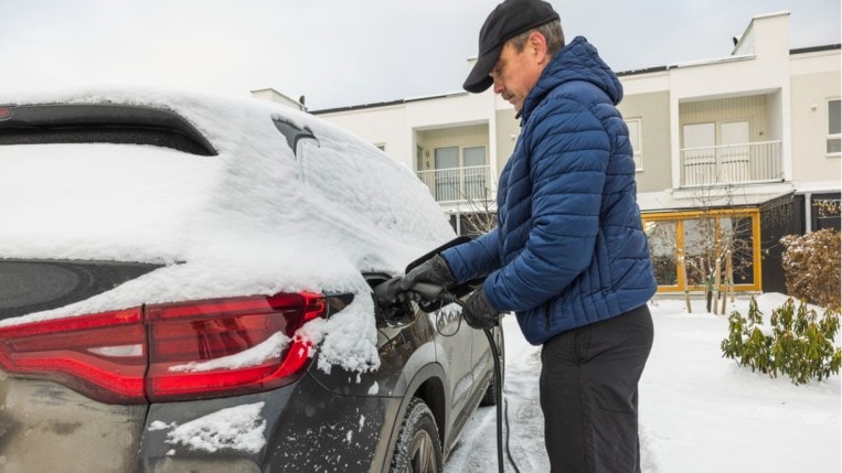 Person charging EV in the snow