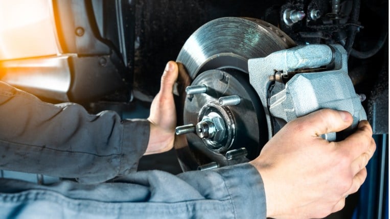 Mechanic checking brake discs on a car.