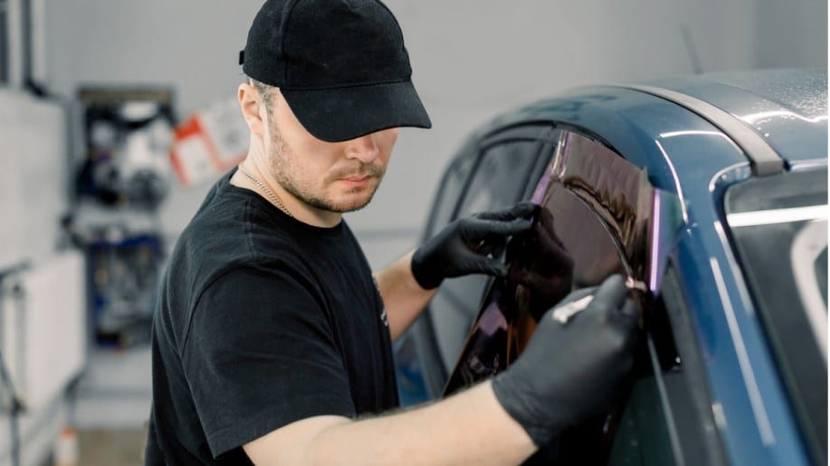 A technician applying tint film to a car window