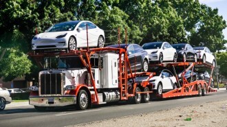 A truck delivering Tesla Model 3 sedans