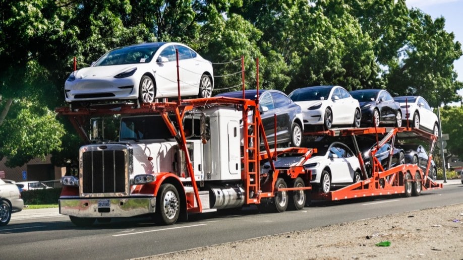 A truck delivering Tesla Model 3 sedans