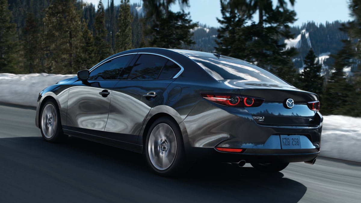 Grey 2023 Mazda3 driving near snow bank.