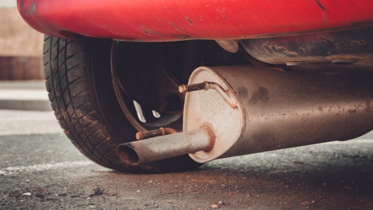 A bad car muffler hanging off a vehicle.
