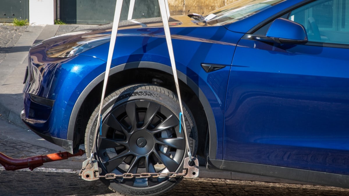 A Tesla Model Y being lifted onto a tow truck.