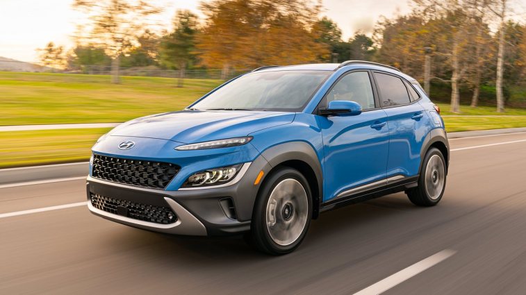 Blue 2023 Hyundai Kona Limited driving by a park.