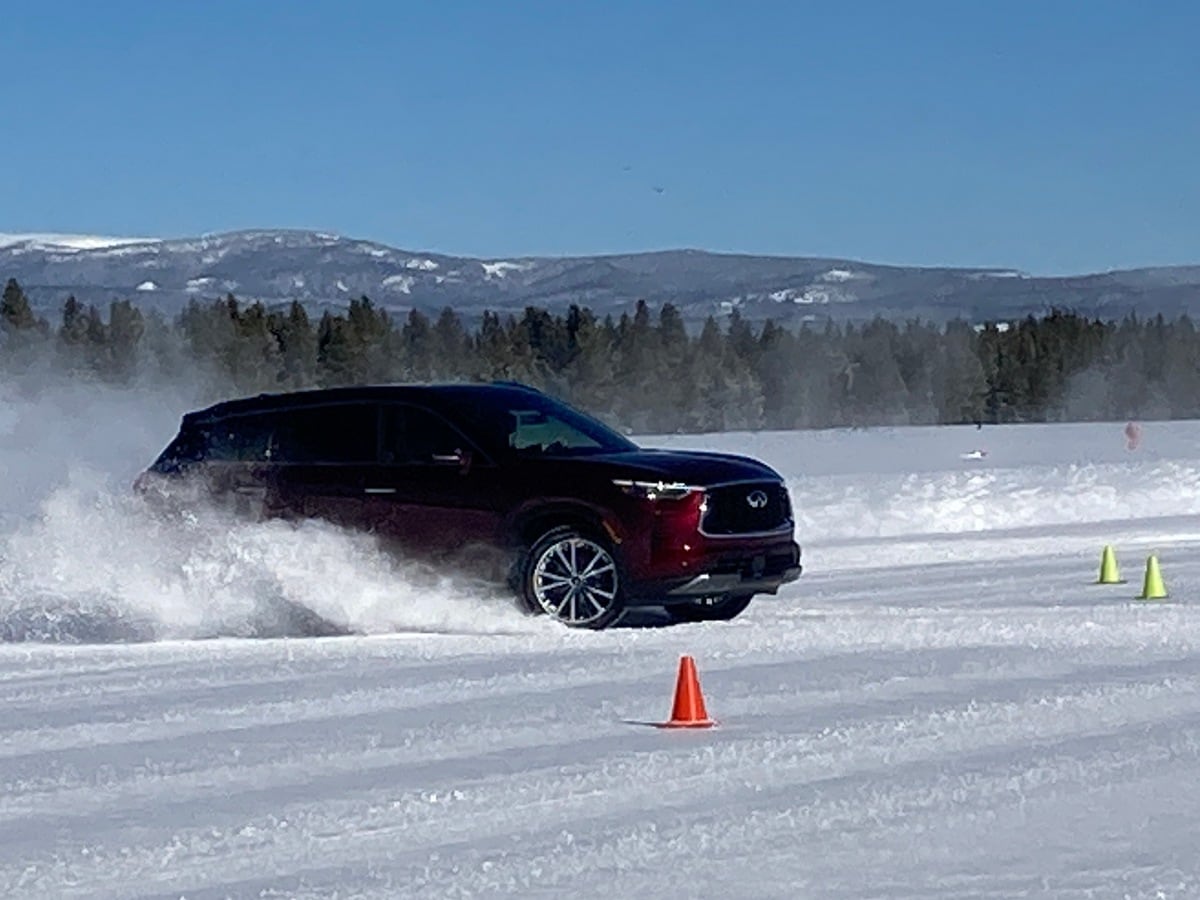 Burgundy 2023 Infiniti QX60 driving in snow.