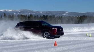 Burgundy 2023 Infiniti QX60 driving in snow.