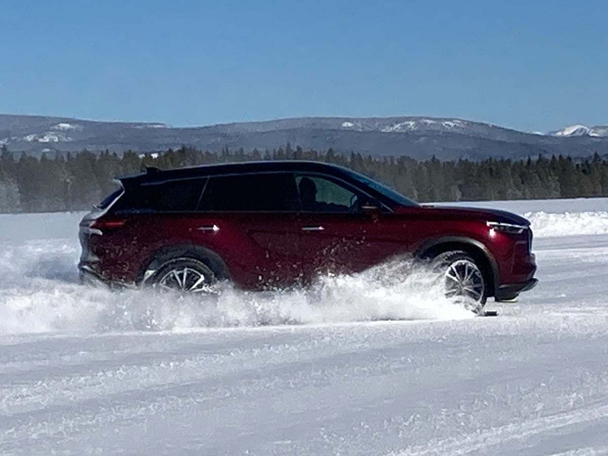 Burgundy 2023 Infiniti QX60 driving in snow.