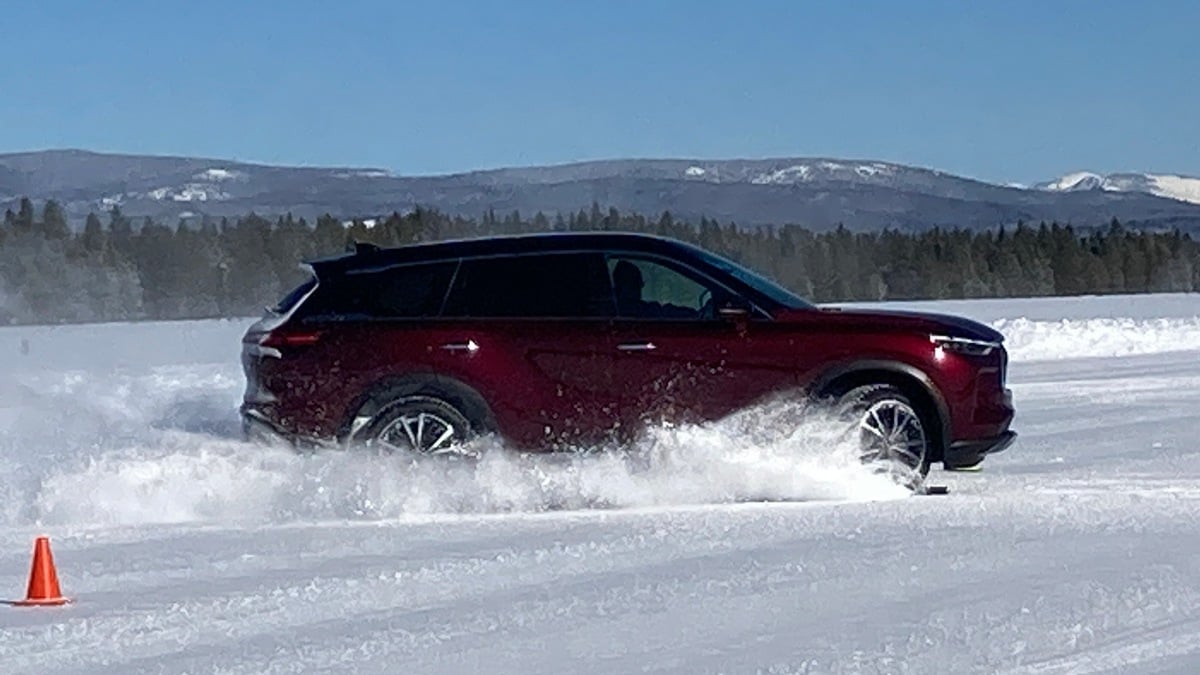 Burgundy 2023 Infiniti QX60 driving in snow.