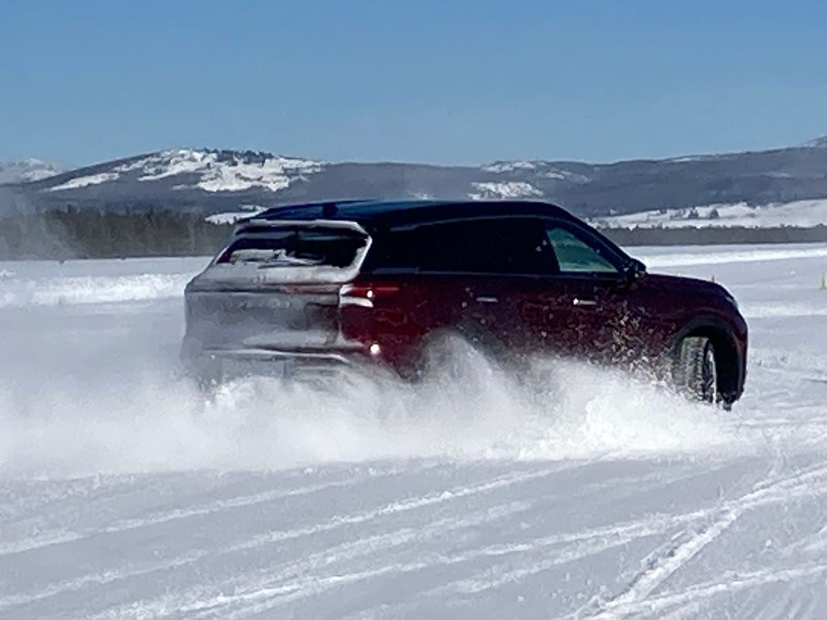 Burgundy 2023 Infiniti QX60 driving in snow.