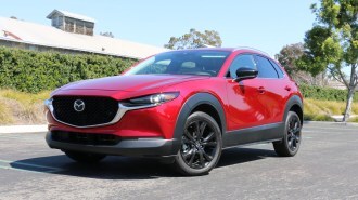 Red 2023 Mazda CX-30 with a green hedge in the background.