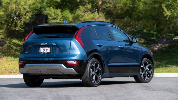 Blue 2023 Kia Niro PHEV near pine trees.