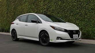 White 2023 Nissan Leaf near ivy wall.