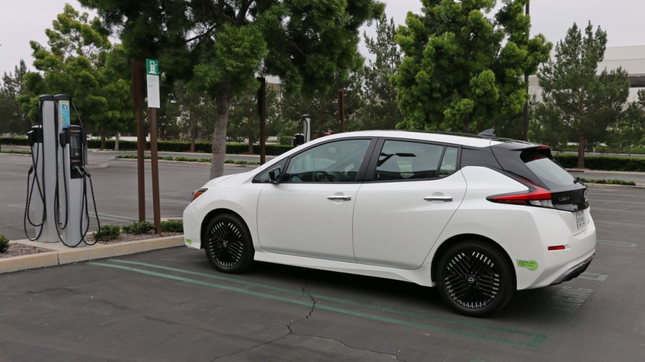 White 2023 Nissan Leaf near EV charger.
