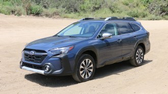 Blue 2023 Subaru Outback Touring on a dirt road.
