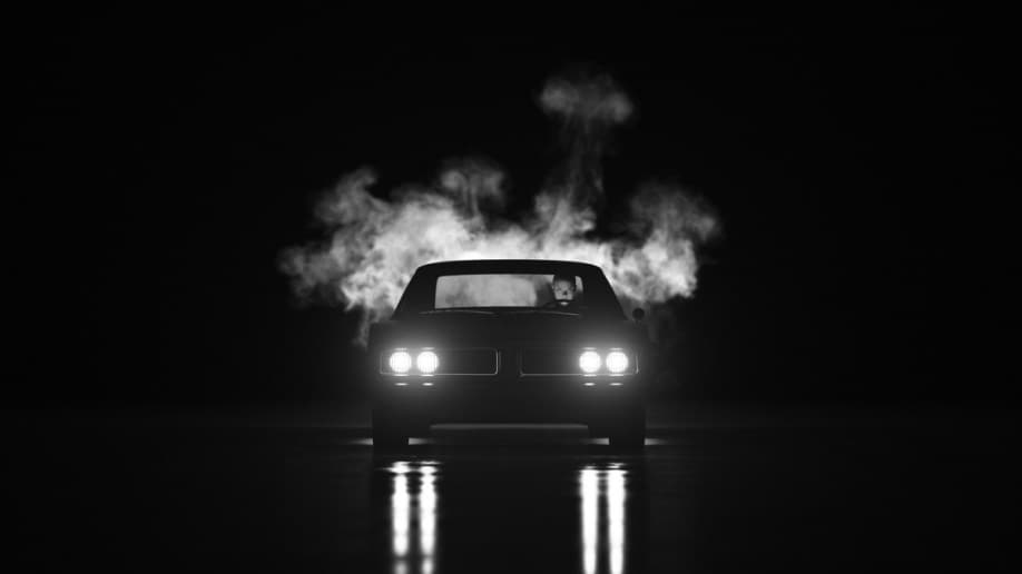 Exhaust from a muscle car with headlights in the dark.
