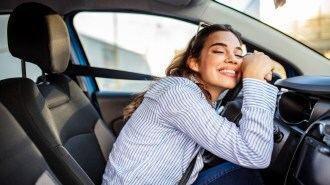 A woman hugging her car steering wheel