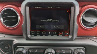 A Jeep's UConnect screen displays an emergency vehicle alert