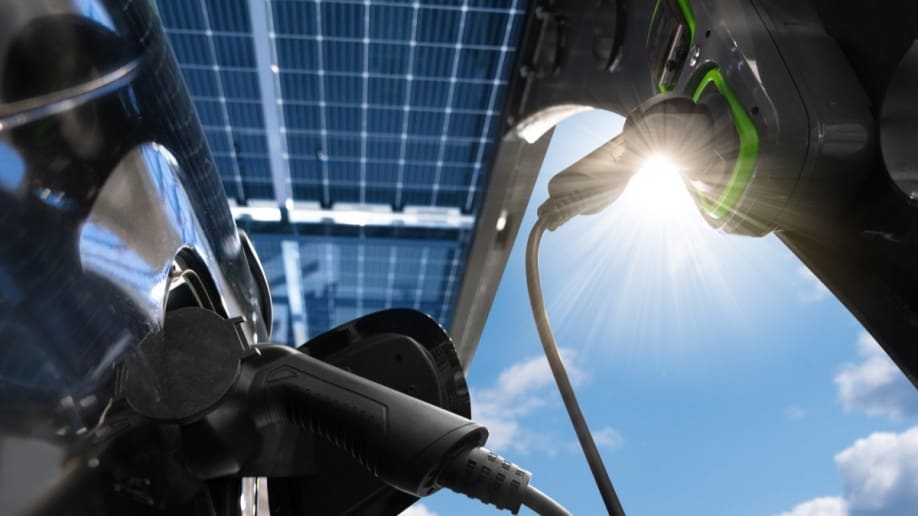 A closeup of an electric vehicle charger silhouetted against the glare of the sun