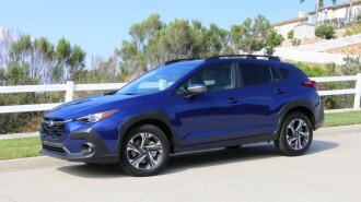 2024 Subaru Crosstrek in blue near white fence.