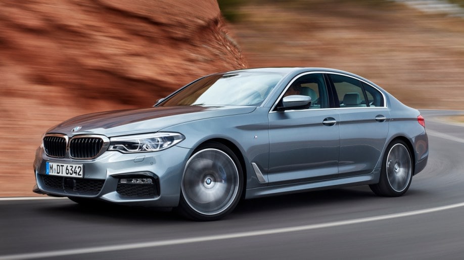 2015 BMW 5 Series in silver driving on mountain road.