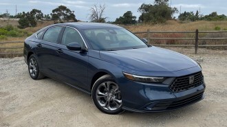 2023 Honda Accord 1.5T EX in dark blue near a wooden fence.