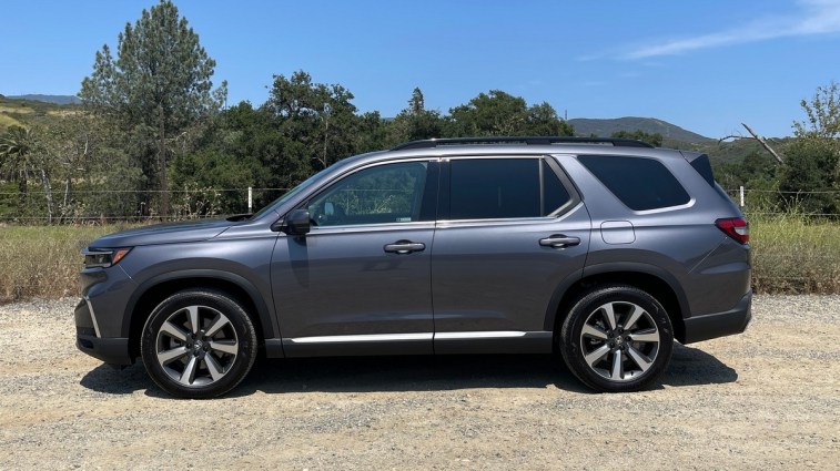2023 Honda Pilot Elite AWD in grey near trees.