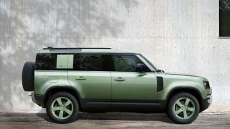 2023 Land Rover Defender 110 75th Edition in green next to a wall.