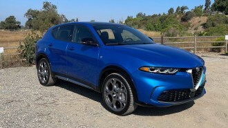 2024 Alfa Romeo Tonale in blue near a wooden fence.