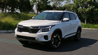 2024 Kia Seltos SX in white near grass and trees.