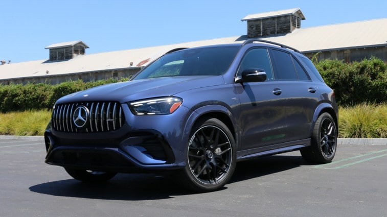 2024 Mercedes-AMG GLE53 in blue near green hedges.