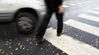 A car perilously close to a pedestrian in a pedestrian crossing