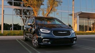 2023 Chrysler Pacifica PHEV Pinnacle in green in front an office building.