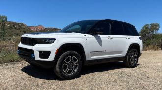 2023 Jeep Grand Cherokee Trailhawk 4xe in white with red hills in the background.