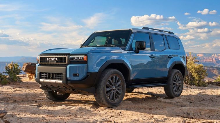 2024 Toyota Land Cruiser in blue on sand with canyon in the background.